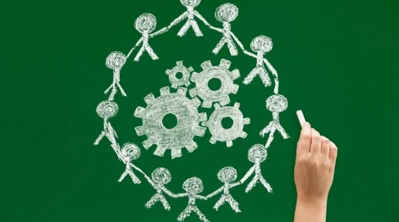 Mão desenhando uma corrente humana no quadro verde que representa a cooperativa