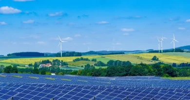 Área campestre com painéis solares e cata ventos sob céu azul
