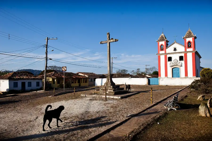 Igreja Matriz de Lavras Novas com a grande cruz e praça de terra, um ponto turístico da histórica vila em Minas Gerais.