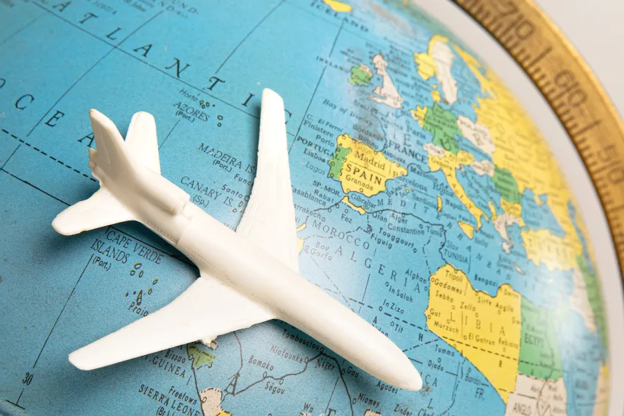 Avião de brinquedo branco sobre globo terrestre, simbolizando os 5 passeios de aventura mais épicos do mundo.