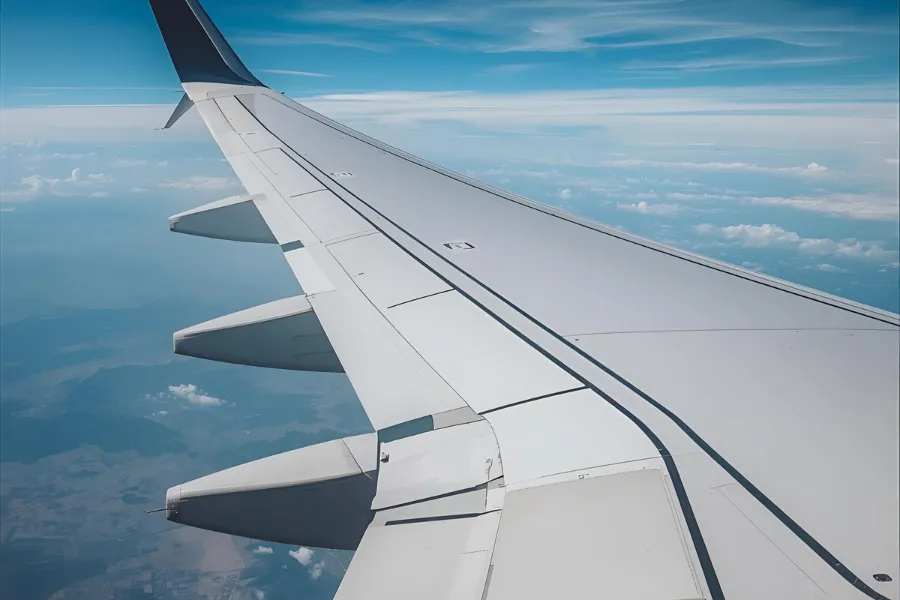 Asa de avião comercial sobre as nuvens, representando a busca por promoções de passagens aéreas na madrugada.